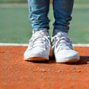 Running shoes on a tennis court, representing footwork